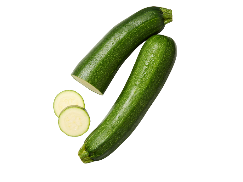 Zucchine verdi fresche, intere e a fette, su sfondo nero.