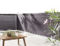 Schermo privacy grigio per balcone con tavolo in legno e piante.