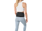 Donna con top bianco, leggings azzurri e fascia lombare nera.