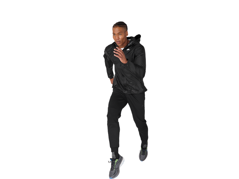 Uomo che corre con giacca nera, pantaloni della tuta e scarpe da ginnastica.