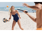 Donna in costume da bagno che gioca a beach tennis in spiaggia.