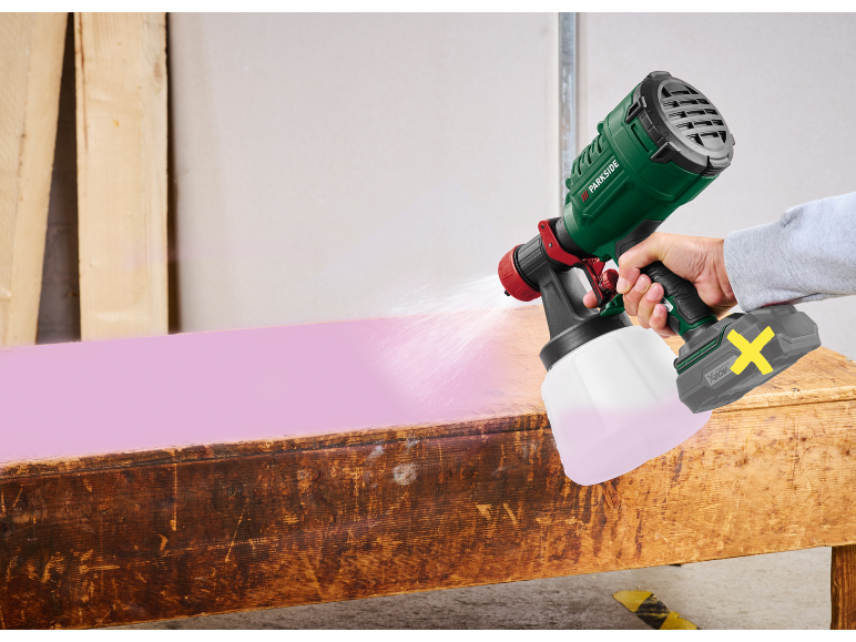 Pistola a spruzzo senza fili vernicia una panca di legno di rosa.