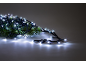 Rami di abete con luci di Natale bianche brillanti su sfondo grigio.