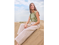 Donna con top verde senza maniche e pantaloni beige seduta su una duna di sabbia.