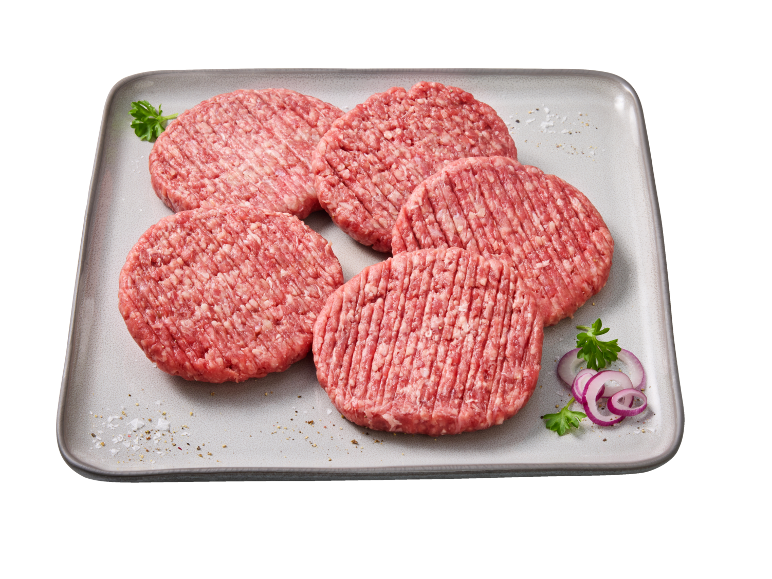 Cinque hamburger crudi su un piatto grigio, guarniti con prezzemolo e cipolle.