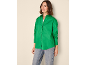 Donna in camicia verde abbottonata e jeans blu, che guarda di lato.