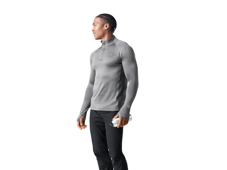 Uomo in maglia sportiva grigia a maniche lunghe e pantaloni neri, con borraccia.