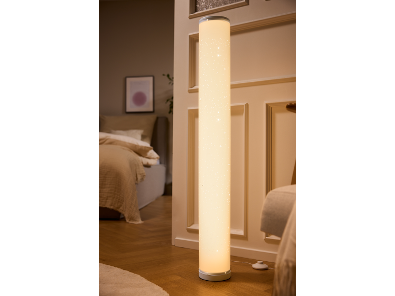 Lampada da terra cilindrica con motivo a stelle che illumina una camera da letto accogliente.