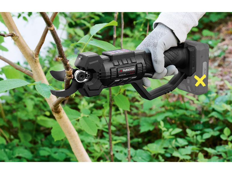 Forbici da potatura elettriche senza fili che tagliano un ramo d'albero in un giardino