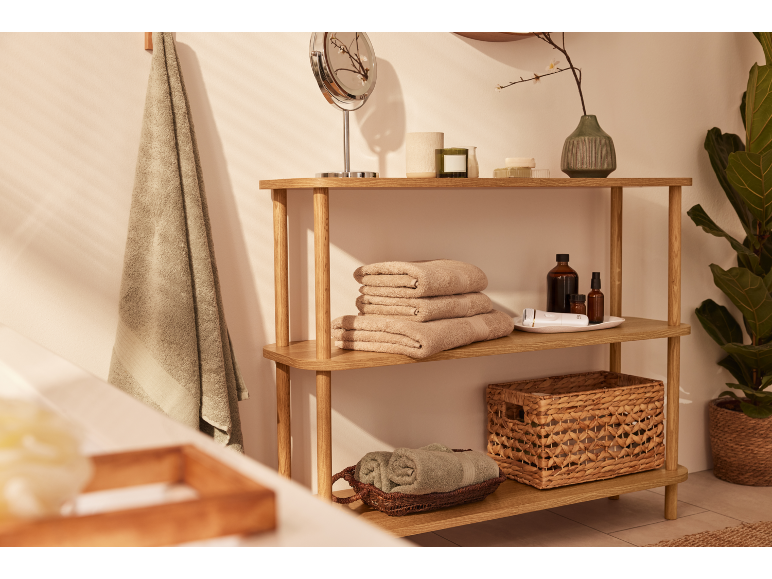Scaffale in legno con asciugamani, prodotti da bagno e decorazioni in un bagno.