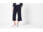 Pantaloni culotte e giacca blu scuro da donna, con sneakers bianche.