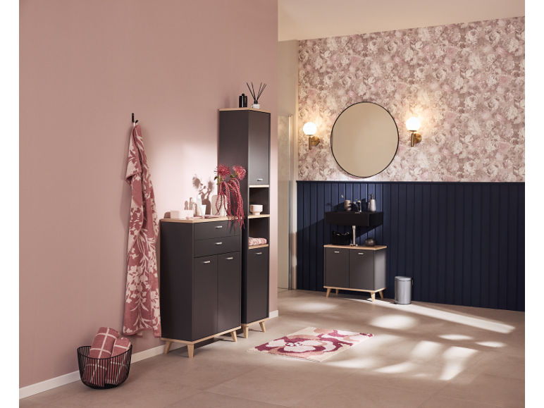 Elegante bagno con mobili grigio scuro, parete rosa e carta da parati floreale.