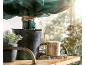 Pianta in vaso con copertura protettiva verde e spago da giardinaggio su una mensola di legno.