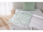 Borsa sottovuoto con biancheria da letto verde su un letto bianco, con cuscino e coperta.