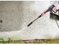 Persona pulisce un muro sporco con un'idropulitrice, rimuovendo alghe verdi.