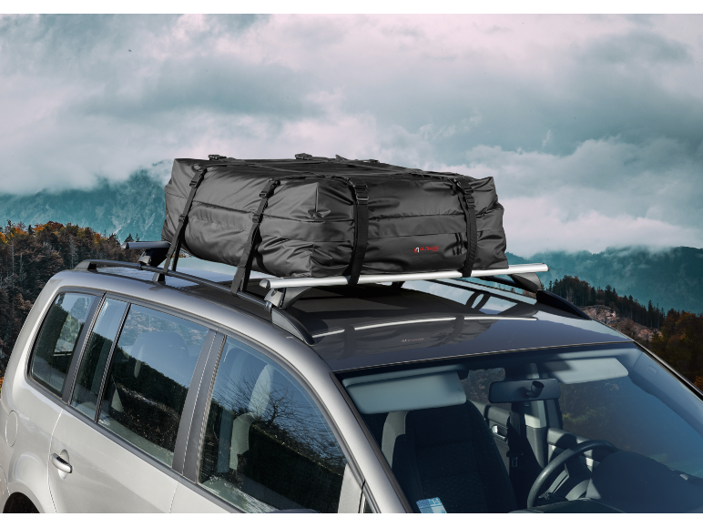 Borsa da tetto nera su un'auto, con un paesaggio montano sullo sfondo.