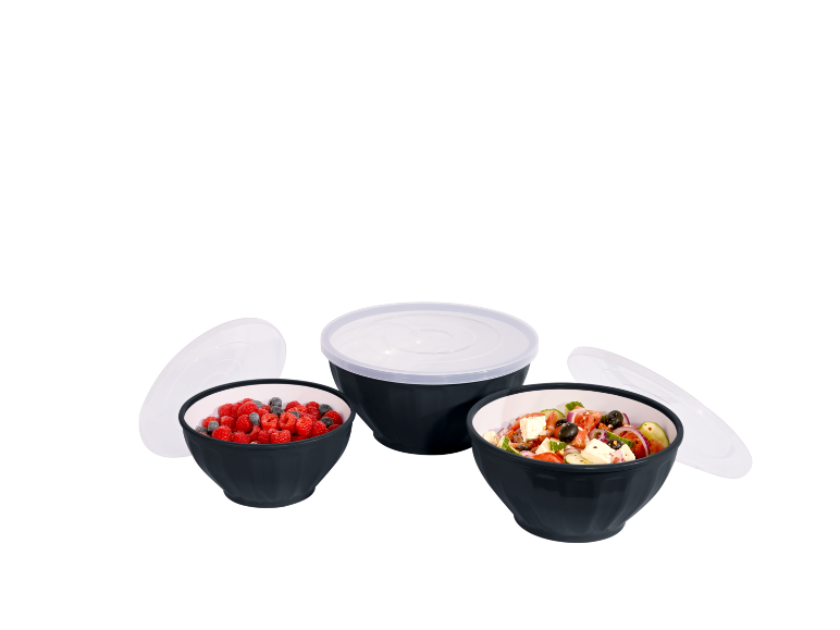 Tre ciotole nere con coperchi bianchi, piene di frutta e insalata.