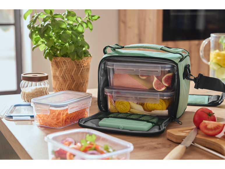 Borsa termica con contenitori per alimenti, fichi e barbabietole, su un tavolo di legno.