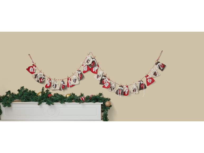 Calendario dell'Avvento natalizio con sacchetti di stoffa numerati appesi sopra un caminetto decorato.