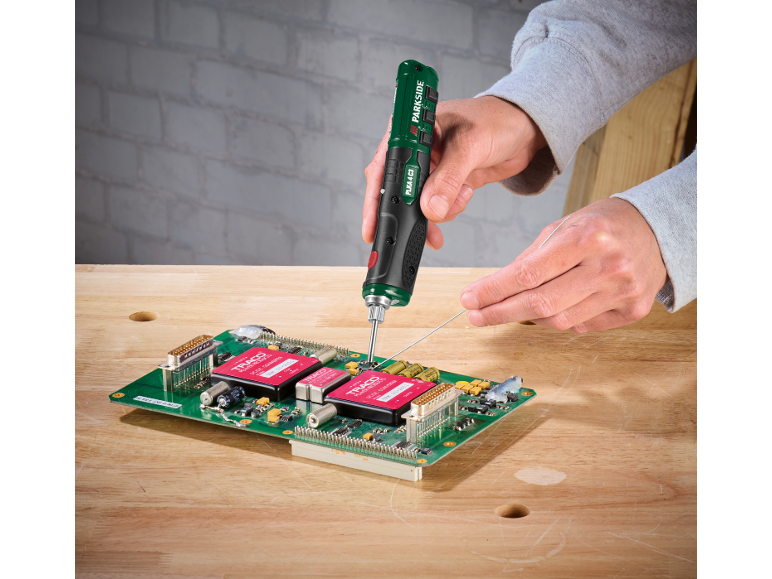 Persona che salda una scheda elettronica con un cacciavite di precisione a batteria e filo di stagno.