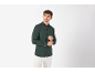 Uomo in camicia verde scuro a maniche lunghe e pantaloni bianchi, che si sistema il polsino.