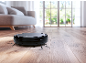 Robot aspirapolvere su pavimento in legno in un soggiorno luminoso.