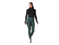 Donna con top nero a maniche lunghe e leggings verde scuro che tiene una borraccia.