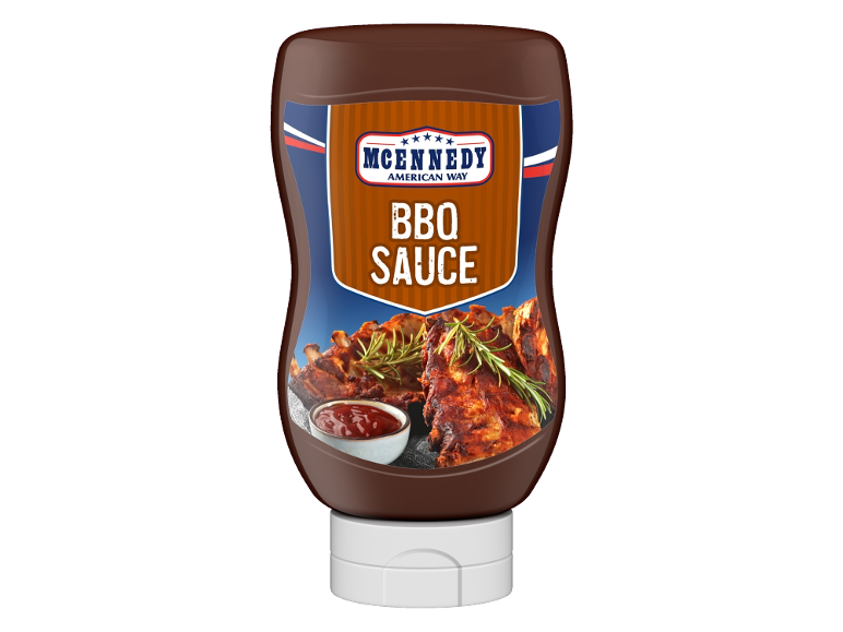 Bottiglia di salsa barbecue con costolette alla griglia e una ciotola di salsa.