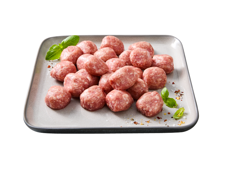 Polpette crude su un piatto, guarnite con basilico e spezie.