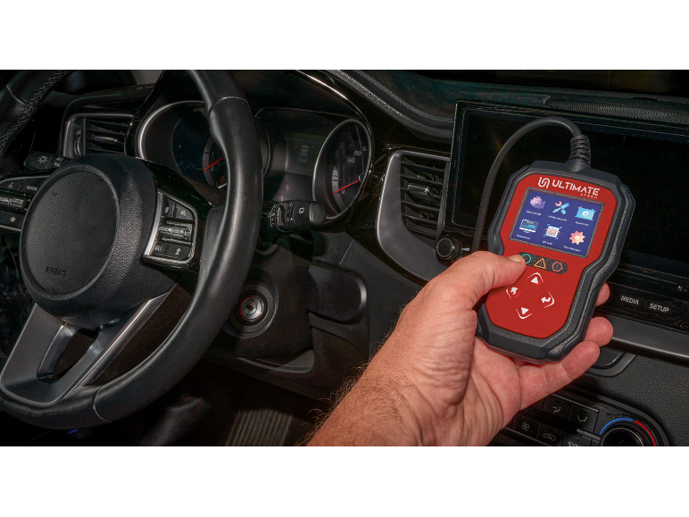 Mano che tiene uno strumento diagnostico per auto con uno schermo che mostra varie funzioni all'interno di un'auto.