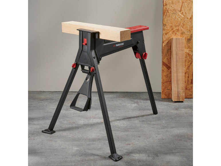 Cavalletto da lavoro nero e rosso con un pezzo di legno, su pavimento in cemento.