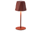 Lampada da tavolo con paralume geometrico e stelo sottile, che emette una luce calda.