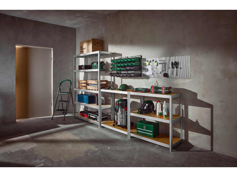 Garage o officina con scaffali, attrezzi, scatole portaoggetti e un aspirapolvere.