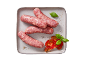 Salsicce crude con pomodori a fette e foglie di basilico su un piatto.