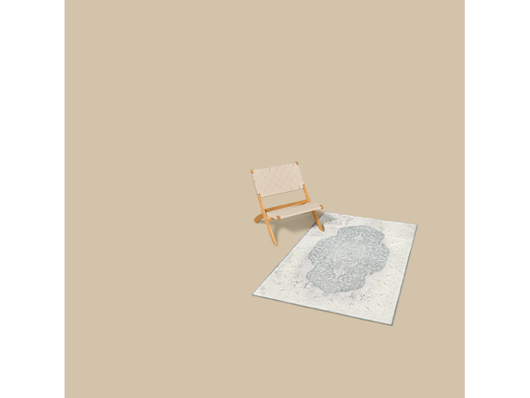 Una sedia pieghevole beige chiaro con seduta e schienale intrecciati, accanto a un tappeto fantasia.