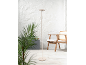 Lampada da terra beige su una terrazza con sedia in legno e pianta.