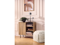 Mobile in legno con pianta, lampade e libri, accanto a un pouf, contro una parete con quadro.