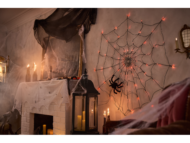 Decorazioni di Halloween con ragnatela illuminata, candele e finto ragnatela.
