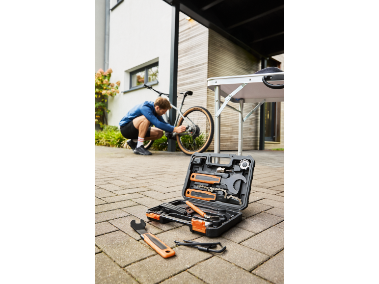 Kit di attrezzi per biciclette con un uomo che ripara una bici all'aperto.