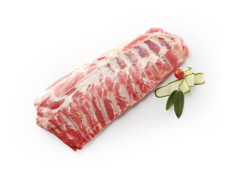 Costine di maiale crude con pomodoro, zucchine e salvia su sfondo scuro.