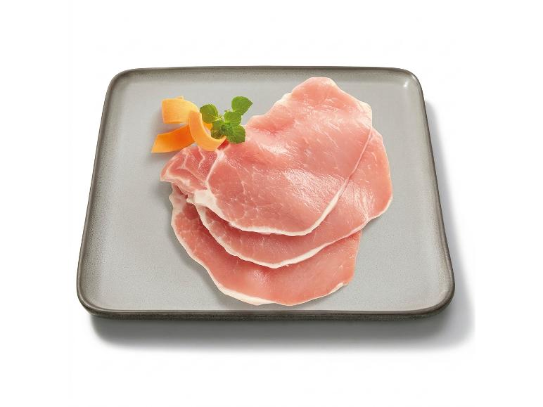 Fette di lonza di maiale cruda con carota e menta su un vassoio rettangolare grigio.