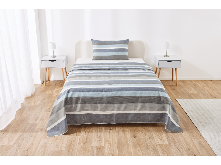 Letto singolo con piumone e cuscino a righe blu, grigie e bianche, con comodini.