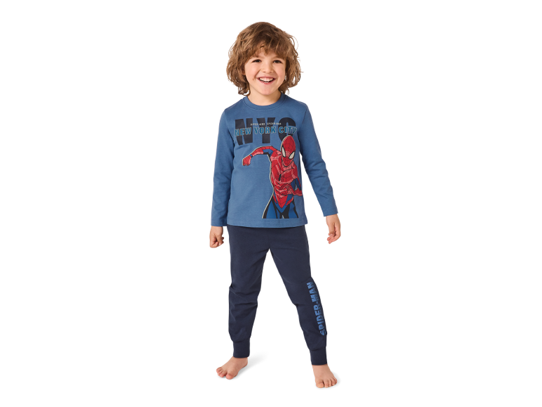 Bambino sorridente in maglia blu a maniche lunghe con grafica di supereroe e pantaloni da jogging blu scuro.