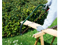 Persona che taglia una tavola di legno con una sega ad arco in un giardino.