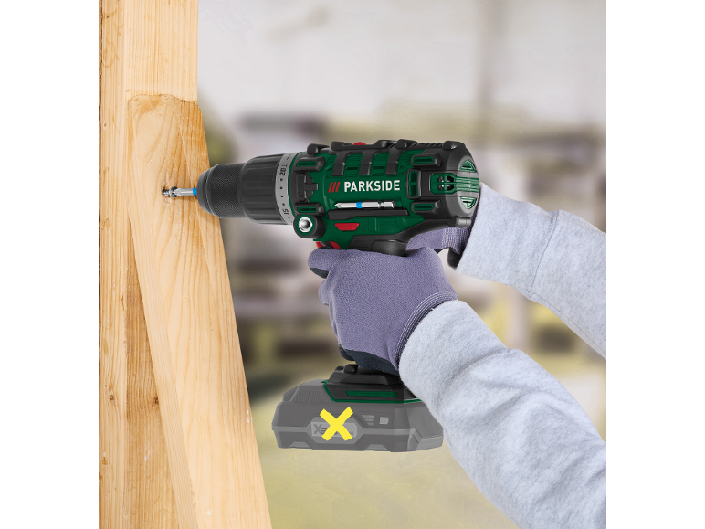 Trapano avvitatore a batteria avvita una vite in una tavola di legno.