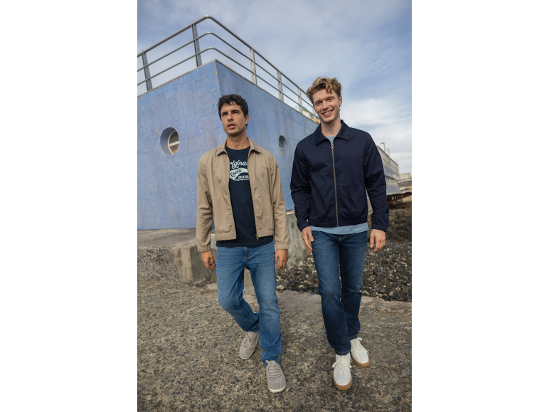 Due uomini in giacche casual, jeans e magliette all'aperto.