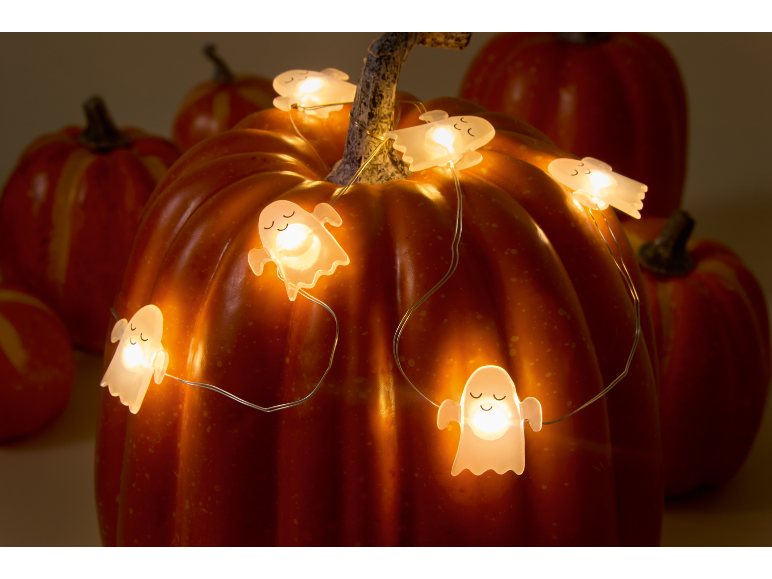 Zucca decorata con una catena luminosa a forma di fantasmi per Halloween.
