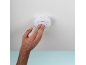 Una mano preme il pulsante di prova su un rilevatore di fumo montato a soffitto.