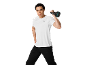 Uomo in t-shirt sportiva bianca e pantaloni neri che tiene un kettlebell.