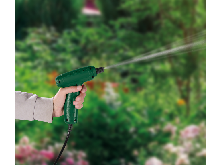 Mano che tiene uno spruzzatore da giardino verde, innaffiando piante in un giardino sfocato.